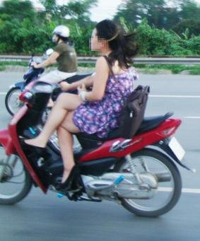 Young girl sits with crossed legs to drive motorbike